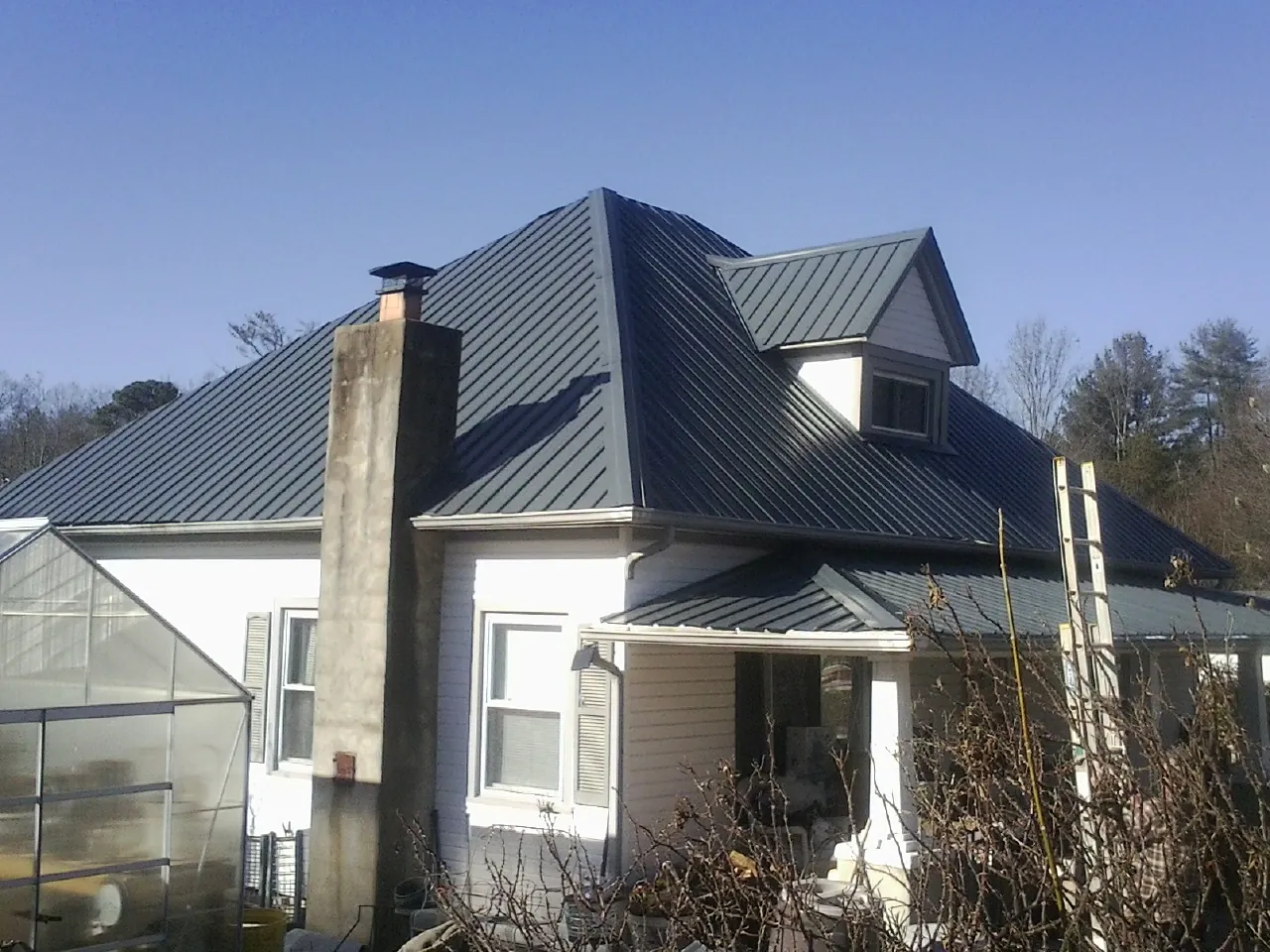 Dark blue standing seam metal roof on a white farmhouse with dormer — Slate & Tile Roof Repair by Roofing Brothers in Keedysville