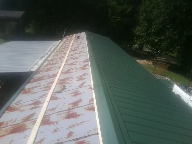 Old rusted panels beside newly installed green metal roofing — Wind Damage Roof Repair by Roofing Brothers in Keedysville
