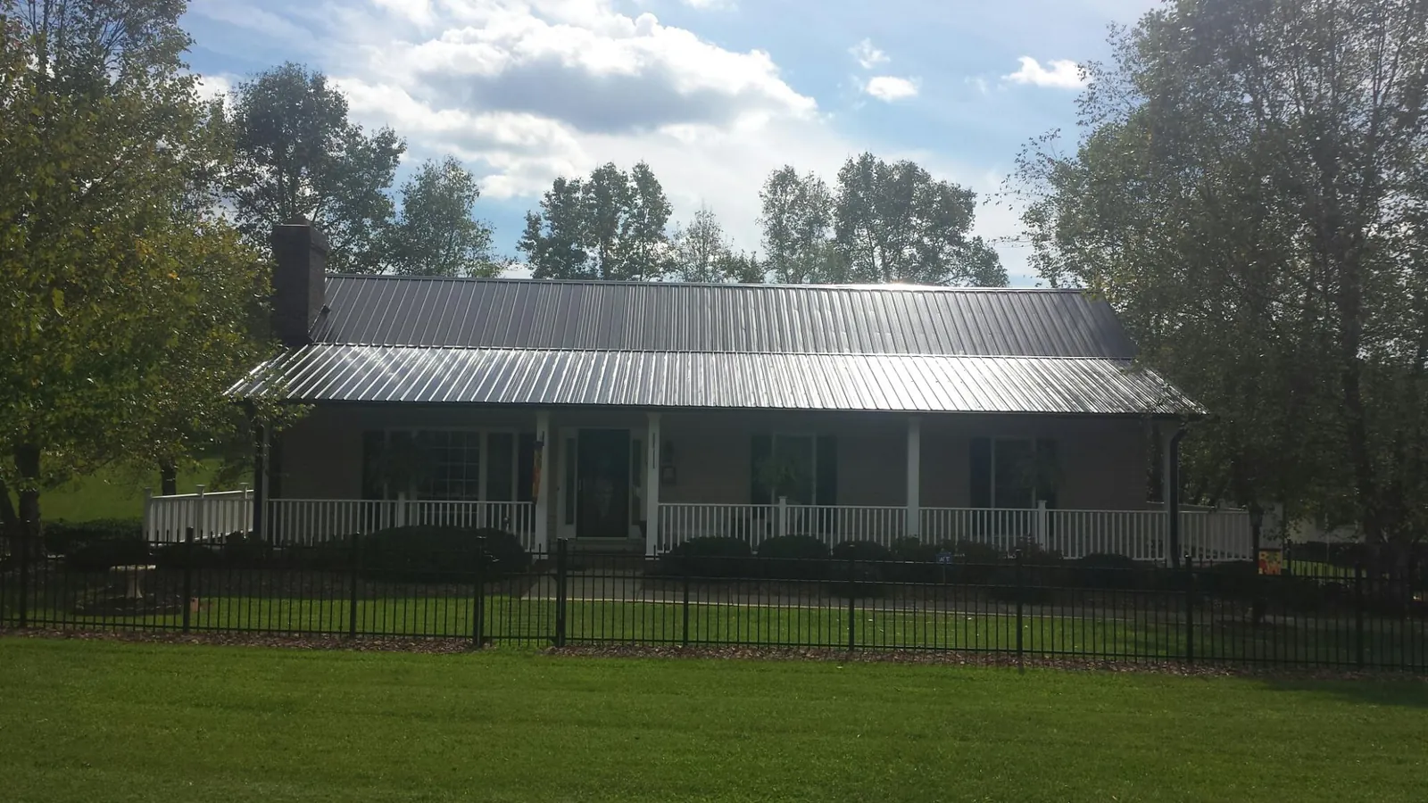 Gray metal roof on a brick ranch with a full width front porch — Gutter Guard Installation work by our crew in Keedysville