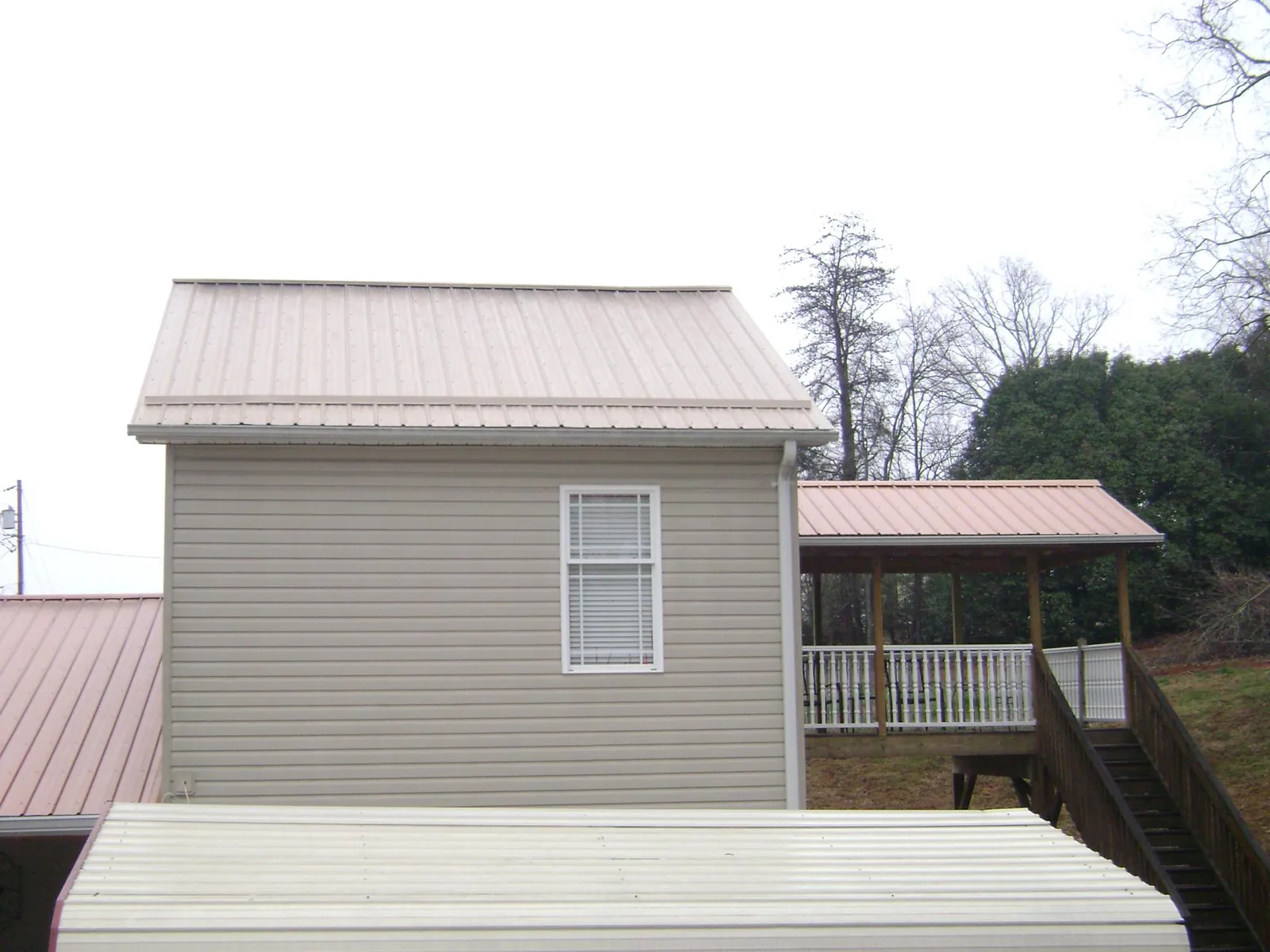 Tan metal roofs on a two story addition and attached porch, from a Roof Replacement job in Keedysville